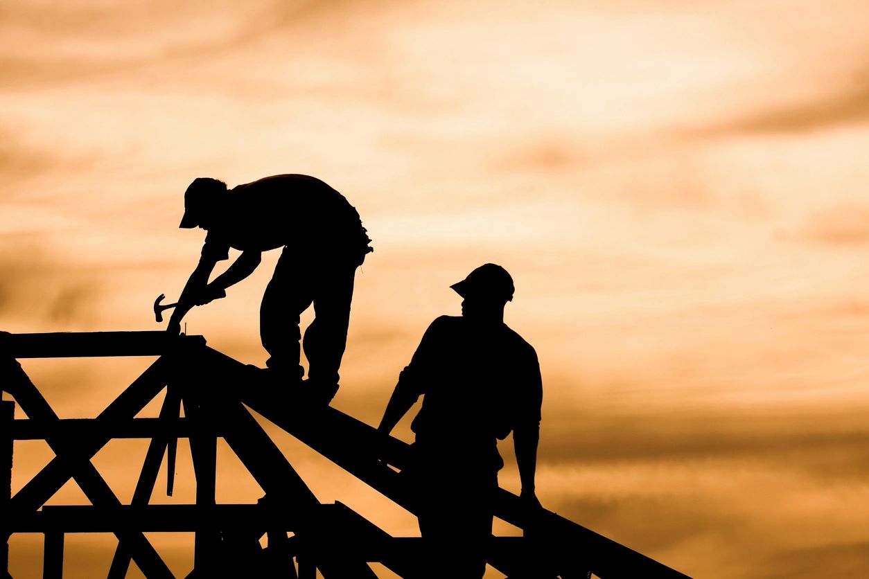 Construction workers silhouetted at sunset